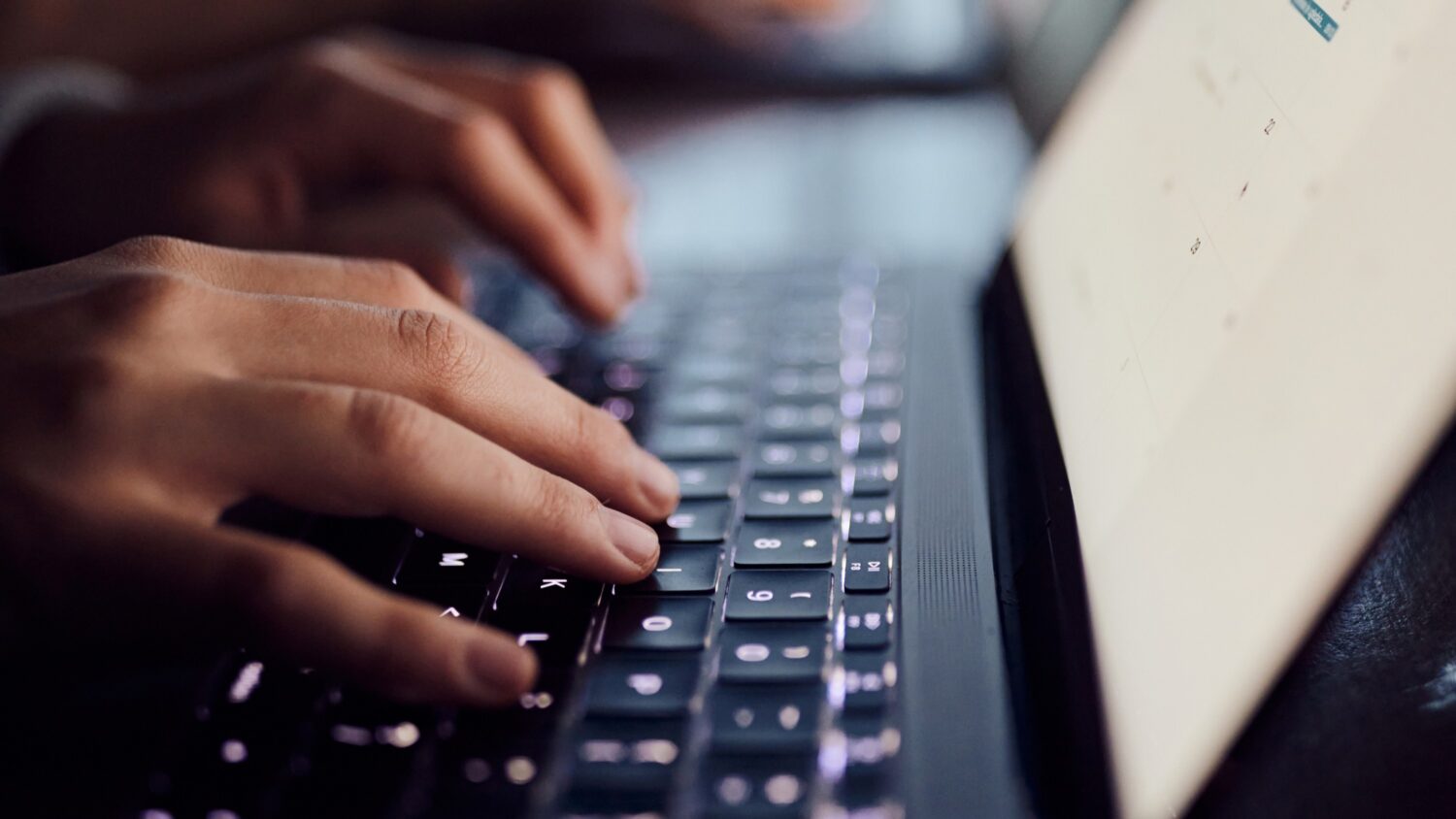 Close-up photo of hands typing on a laptop keyboard